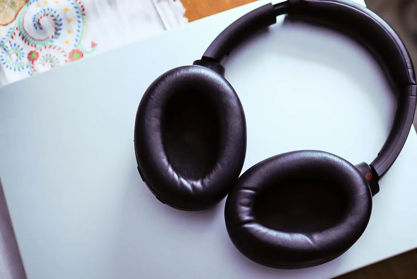 Black head phones are on top of a macbook laptop