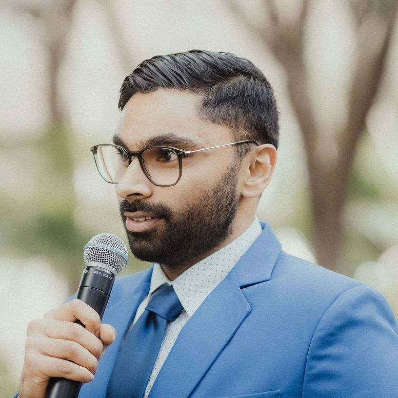 Portrait of a man holding a microphone in a blue suit and tie